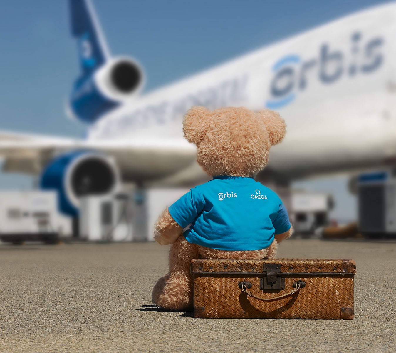 O ursinho de peluche, mascote da Orbis, sentado ao lado da aeronave do Flying Eye Hospital da Orbis