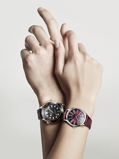 2 embracing hands wearing each an Omega watch
